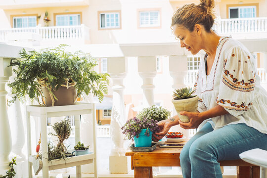 Adult Woman In Gardening Activity Outside Home In The Terrace. Female People Caring Plants For Environment And Green Lifestyle Concept. Happy Lady Regrowth Plants Outside