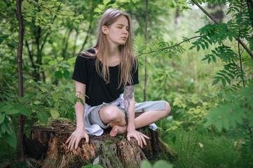 Girl in green forest. Practice of meditation and interaction with nature