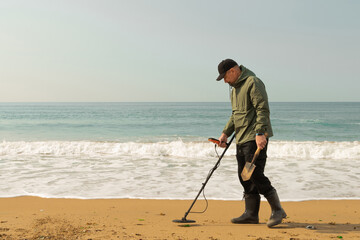A man with a metal detector and a shovel on the seashore. A treasure hunter with a metal detector....