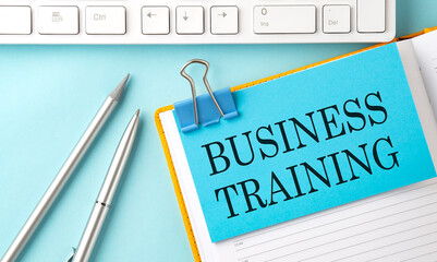 BUSINESS TRAINING text on blue sticker on the planning and keyboard,blue background