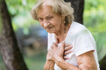 Elderly woman with heart pain holding her chest