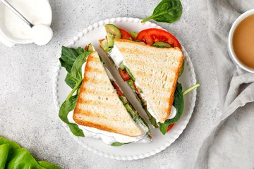 Foto op Canvas Sandwich cut in half. Two pieces of delicious vegetarian sandwich with lettuce, tomatoes and sauce. Top view © Maria