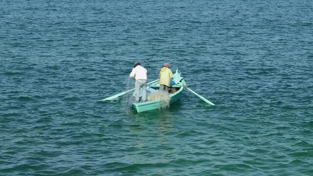 Fishermen on rowboat cast net into sea water. Poachers are engaged in fishing. Men standing in boat, waiting for fish catch. Fishers ship floating on waves. Fishery, lifestyle, hobby