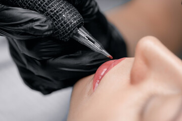 Process applying permanent makeup tattoo of red on lips woman in beautician salon - obrazy, fototapety, plakaty