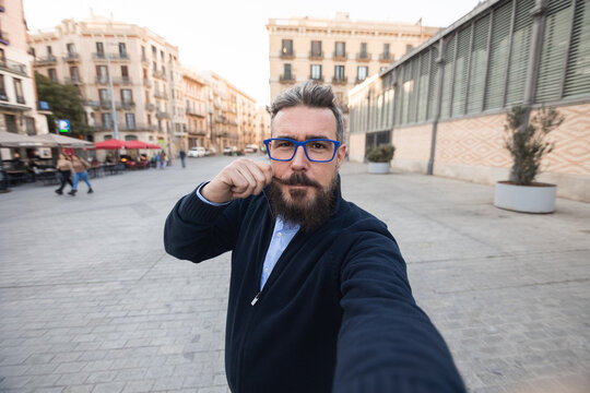 Mid adult man taking selfie while touching his mustache in center of Barcelona