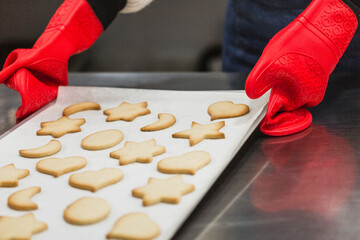 Close up of woman leaving tray with hot cookies on table