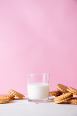 Sandwich cookies and a glass of milk on a pink background. The concept of breakfast and a quick...