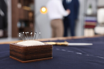 Dressmaker working in atelier, focus on pin cushion. Space for text