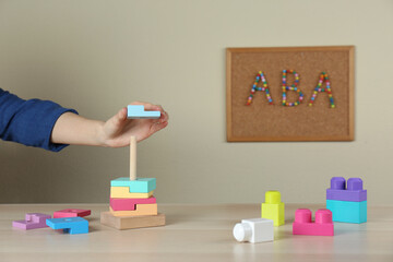 Child playing with toy pyramid at wooden table indoors, closeup. ABA therapy concept - obrazy, fototapety, plakaty