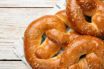Delicious pretzels with sesame seeds on white wooden table, closeup
