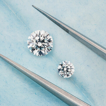 Large and Smaller Round Diamonds Between Tweezers in Blue Diamond Parcel
