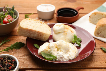 Delicious burrata cheese with basil on wooden table, closeup