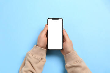 Man with smartphone on light blue background, top view