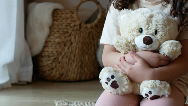 Child hugs and cuddles a cute beige teddy bear
