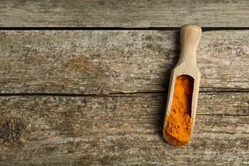 Scoop with saffron powder on wooden table, top view. Space for text
