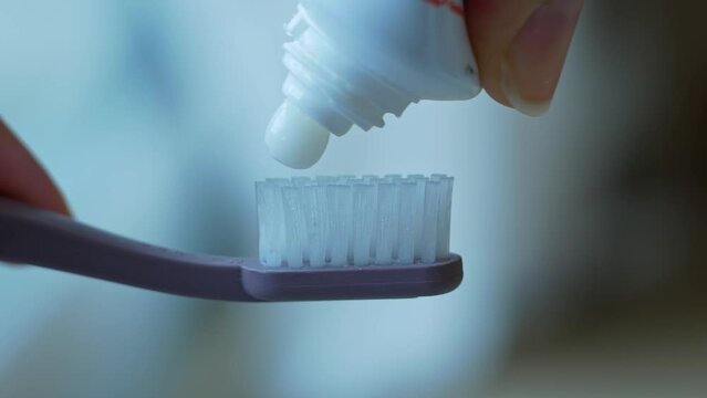 Close-up of squeezing toothpaste onto a recycled plastic toothbrush