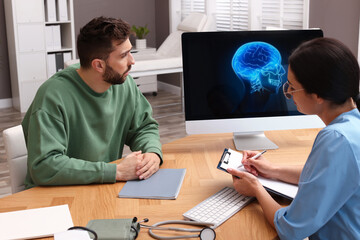 Neurologist consulting patient at table in clinic - obrazy, fototapety, plakaty