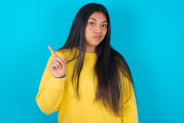 No sign gesture. Closeup portrait unhappy young latin woman wearing yellow sweater over blue...