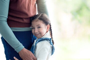 Cute little girl hugging her father around the waist with love, smiling and looking at camera,...