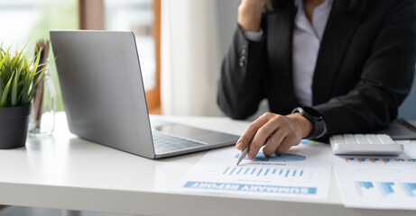 Business or bookkeeper woman pen pointing turnover with graph chart report and use laptop computer...