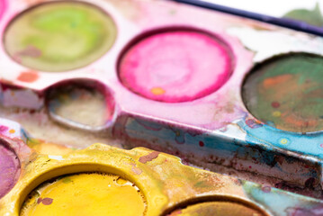 Blurry watercolor paints in close-up. Dirty paint packaging. Accessories for art work for children.