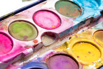 Blurry watercolor paints in close-up. Dirty paint packaging. Accessories for art work for children.