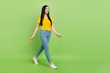 Fototapeta na wymiar Full length profile portrait of adorable satisfied lady walking look empty space isolated on green color background