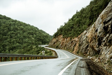 Scenic mountain winding road after the rain. Green forest hills in the background. Cape Breton, Cabot Trail, Nova Scotia, Canada