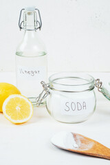 Baking soda in jar, vinegar, cut lemon, wooden spoon on a white background. The concept of removing stains on clothes