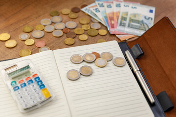 Banknoty euro w portfelu i monety na stole obok notesu z długopisem i kalkulatorem. Koncepcja oszczędzania pieniędzy.
