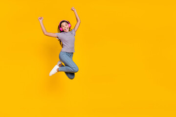 Obraz premium Full body photo of young excited girl have fun rejoice success fists hands melody sound isolated over yellow color background