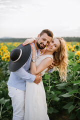 Couple walks in the sunflowers in a field on a summer day