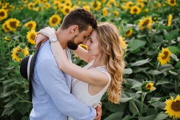 Couple walks in the sunflowers in a field on a summer day