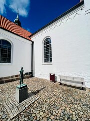 Kirchplatz in der dänischen Hafenstadt Lemvig, mit kleiner Statue und Sitzgelegenheit