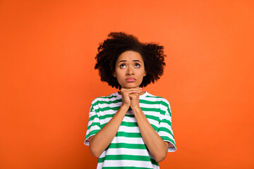 Portrait of attractive miserable girl asking miracle looking up isolated over bright orange color...