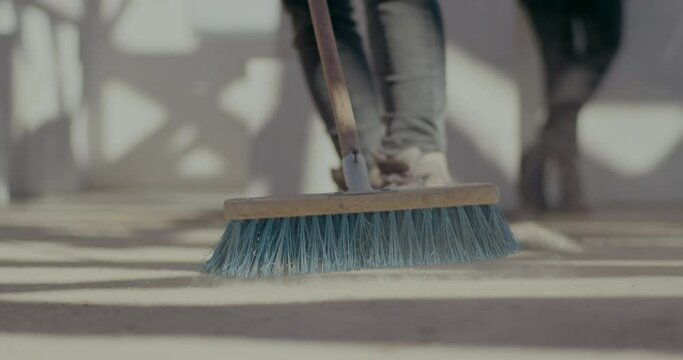 Female worker sweeping floor with broom