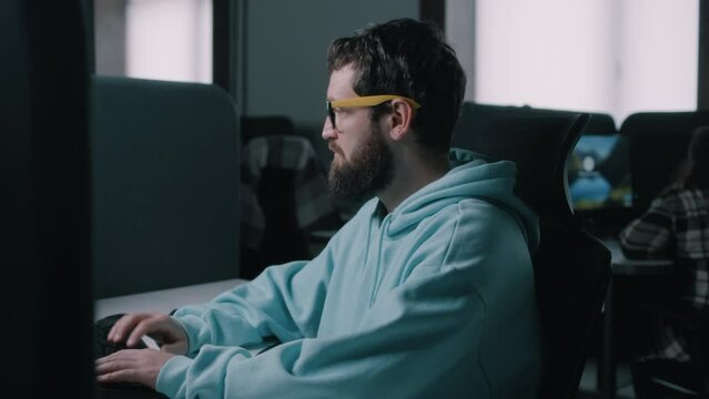 Web developer in glasses working on a computer in IT office during the war and starting to run after an explosion