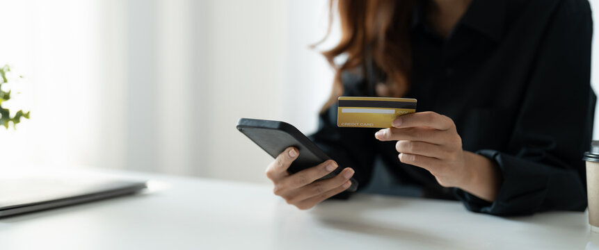 Close up of woman hold bank credit card shopping online using mobile phone, buying goods or ordering online, entering bank accounts and details in online banking offer.