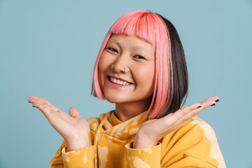 Asian girl with pink hair smiling and holding copyspace