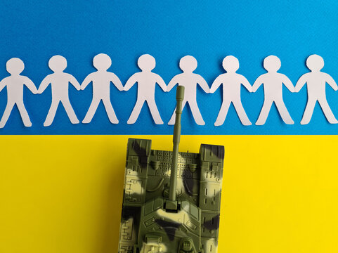 Military tank and people made of paper holding hands against background of Ukrainian flag