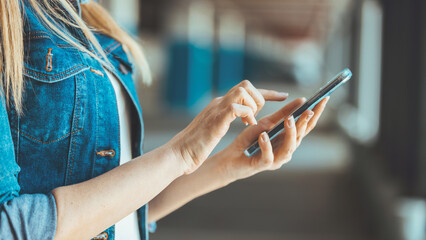 A clip shot of a beautiful young woman using a smartphone. The woman uses a smartphone in the parking lot, exchanges messages or browses social networks.