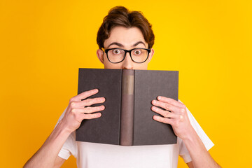 Photo of young man hold book read study eyewear materials novel isolated over yellow color...