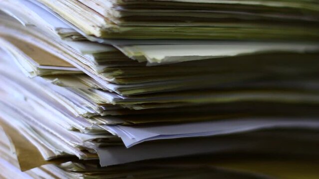 Close up of files, papers, newspapers in a stack on the desk.