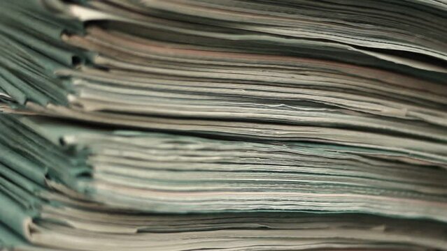 Close up of files, papers, newspapers in a stack on the desk.