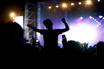 Viewers under the stage. The man with raised hands during summer festival rock concert.
