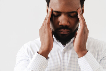 Black tired man wearing shirt with headache rubbing his temples