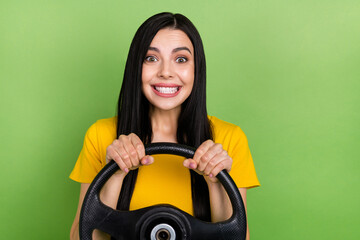 Photo of cheerful pretty lady toothy smile hold wheel look camera isolated on green color background