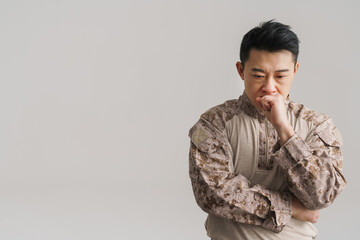 Asian puzzled military man wearing uniform posing on camera - obrazy, fototapety, plakaty
