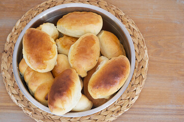 Handmade Russian stile delicious pies with different fillings are cooked in the dark warm oven are preparing for weekend breakfast waiting at the wooden table in the farm kitchen at cozy home.