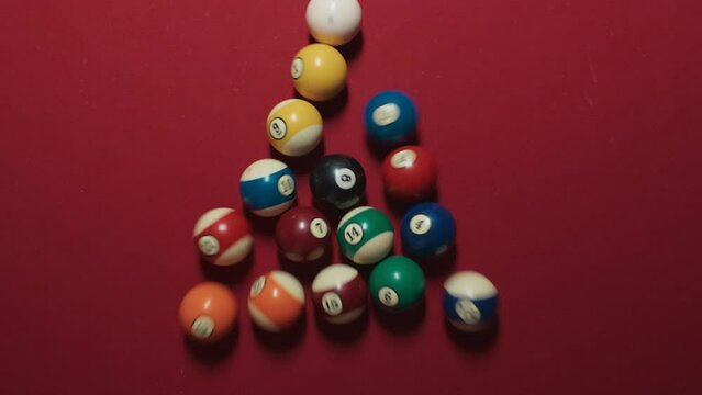 Young woman hand picking up pyramid form before pool game of 15 balls beginning on red felt table. Hobby, professional game, sport, entertainment. 15 colorful balls breaks on top view shot, 4k footage